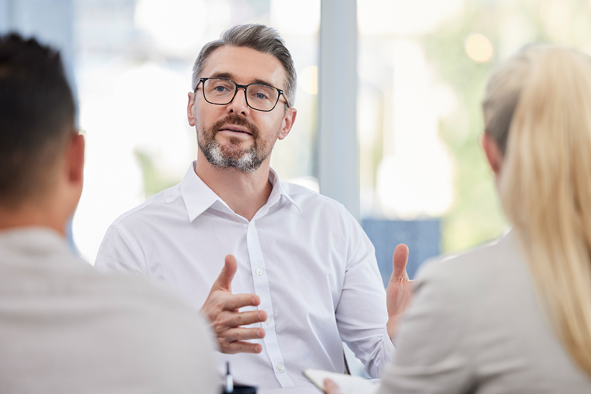 Mann spricht mit zwei Personen bei einem Meeting